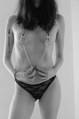 Submissive London escort pulling on her nipples with a chain